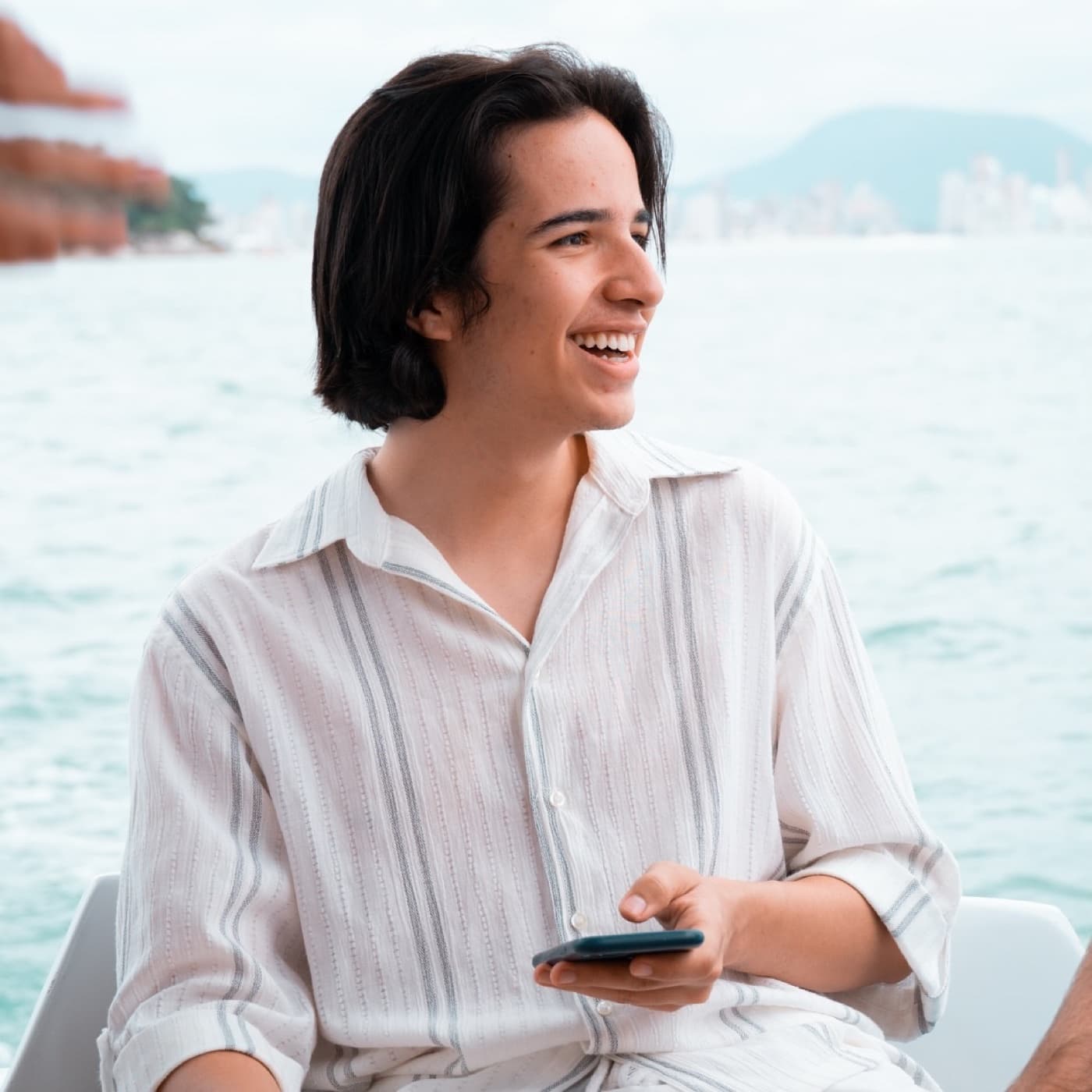 Aluno da Winners sentado num barco, com o celular na mão